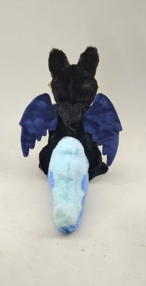 A plush toy based on Whisper the Ghost Fox from The Storyteller Squad. Whisper's plush has dark black fur all over their body, with longer fur around their neck, shoulders, and chest, and shorter fur than the rest of their body on their front and back forelegs. Their white spirit mask covers their face and is made of an off white felt, with embroidery lines added to imply wood grain texture, and an eye hole that reveals a black minky base beneath to imply depth and the existance of a void. They have two small wings on their back which are minky dyed in a gradient from black to dark navy blue, and embroidered with a simple feather pattern. Their tail is made from light blue and cyan blue long fur and shaped like a flame to represent Whisper's ghostly will-o-wisp tail. They are posed in a seated position.